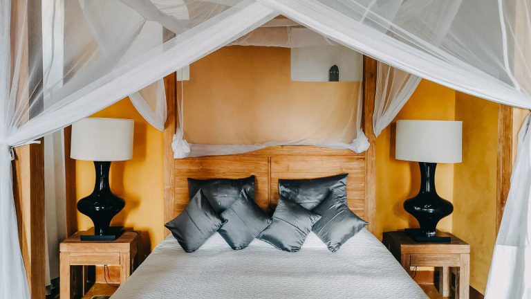 Four-poster bed with grey silk cushions in the French Prestige suite at Kholle House