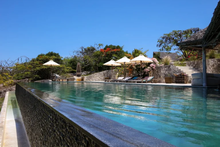 Pool terrace with umbrellas along the coral edge at Qambani