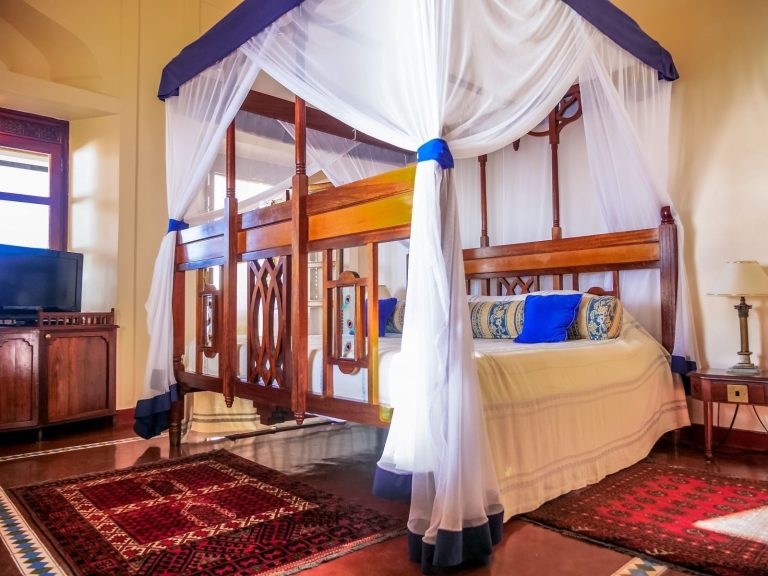 Prime King Room with a carved four-poster bed and mosquito net at Zanzibar Serena Hotel