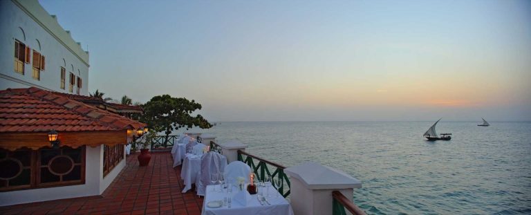 Seafront terrace of Zanzibar Serena Hotel overlooking the Indian Ocean with a dhow at sunset