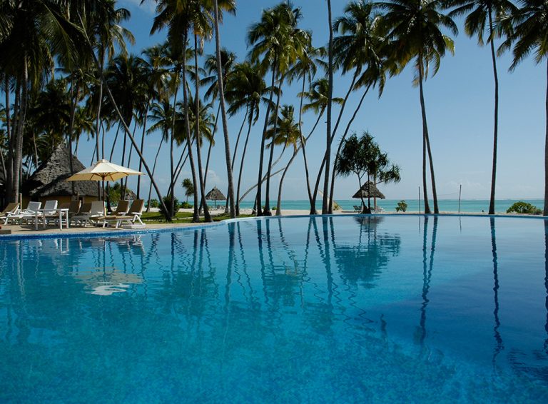 Infinity pool edged by palms looking out to sea at Ocean Paradise Resort