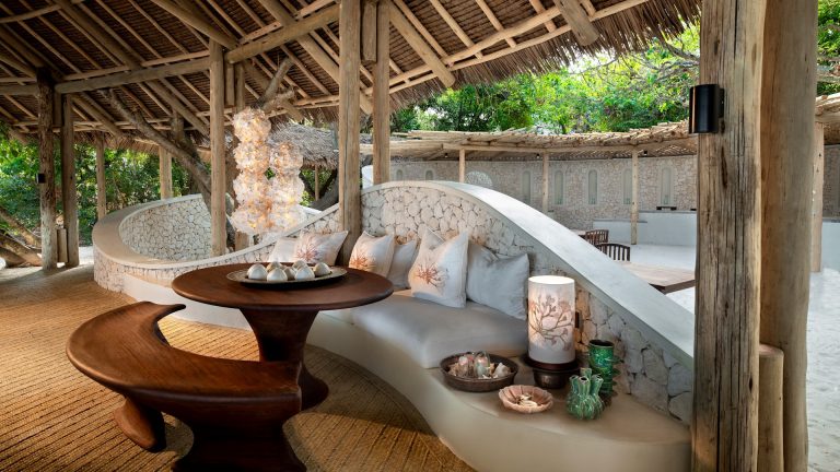 Curved lounge with sculpted seating under a palm-thatch roof at &Beyond Mnemba Island