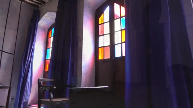 Room at Emerson Spice Hotel with tall stained-glass windows and deep blue curtains