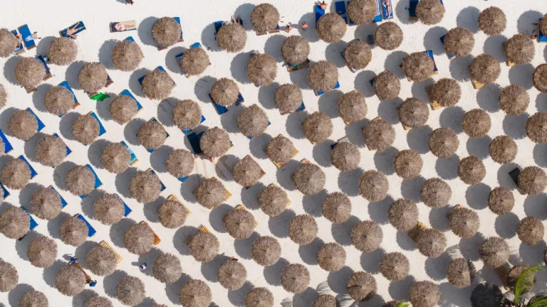 Rows of thatched beach umbrellas on the sand at Kendwa Rocks, seen from above