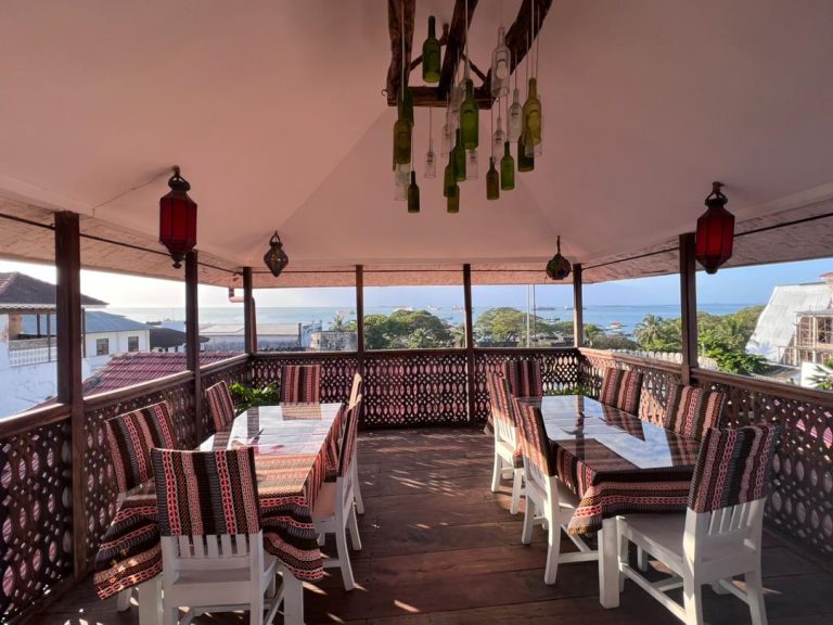 Rooftop restaurant with lanterns and carved railings overlooking Stone Town at Jafferji House