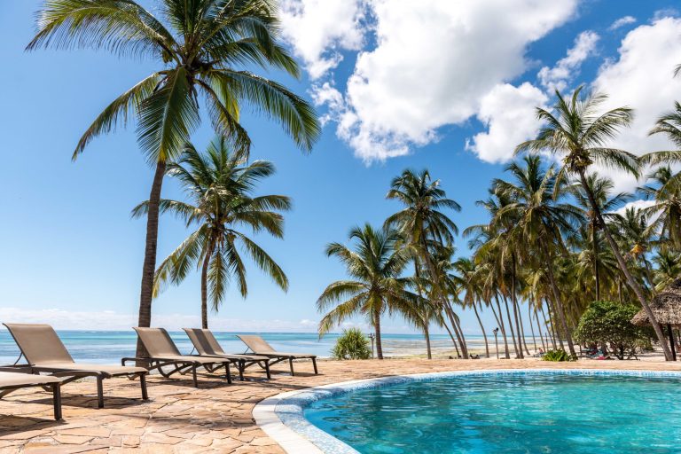 Swimming pool with loungers under palm trees at Karafuu Beach Resort