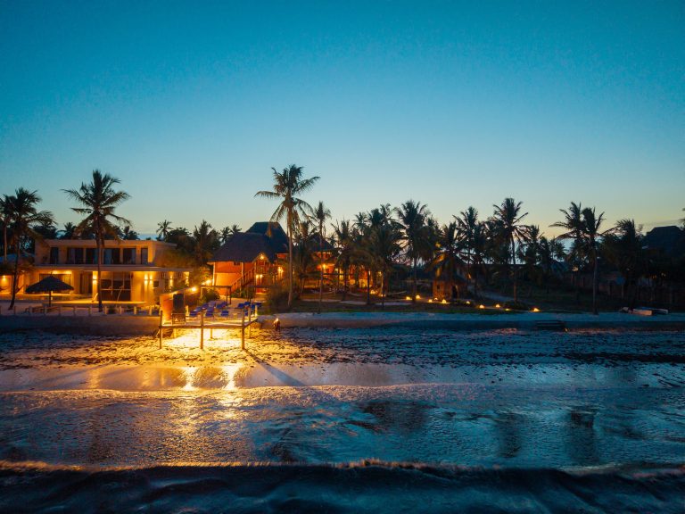 Shanuo Beach Bungalows lit up at dusk across the beach