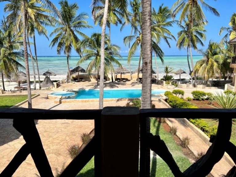 Sea and pool view through palm trees from a first-floor balcony at Zula Zanzibar