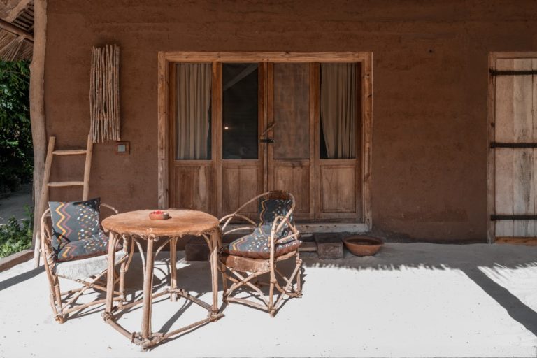 Clay-walled Moon House with wooden doors and veranda seating at Mwezi