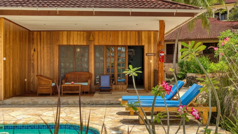 Wooden Pool Bungalow veranda with blue sun loungers at Kendwa Rocks