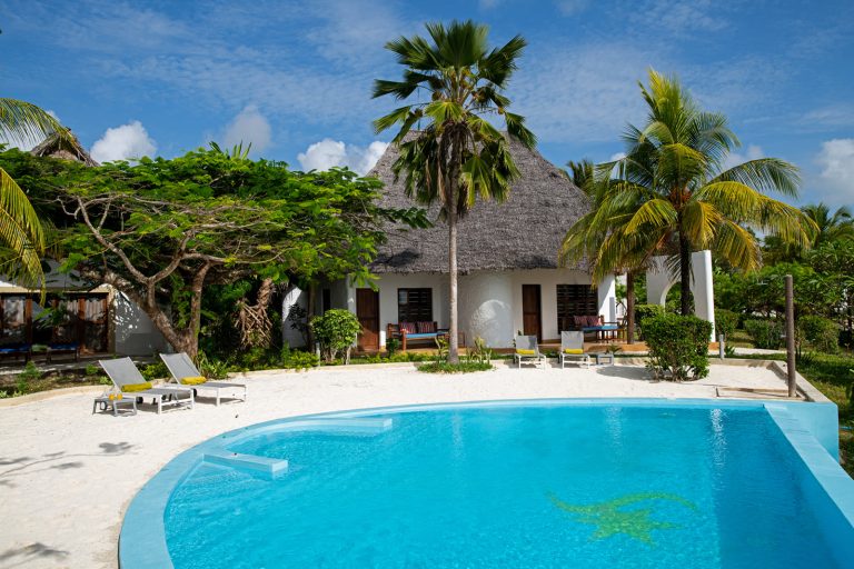 Pool and thatched cottages in the garden at Shooting Star Boutique Hotel