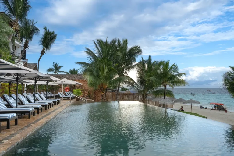 Infinity pool with sun loungers and palm trees at The Z Hotel