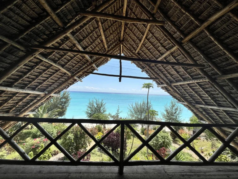 Sea and garden view framed by a makuti thatched roof at Sazani Beach