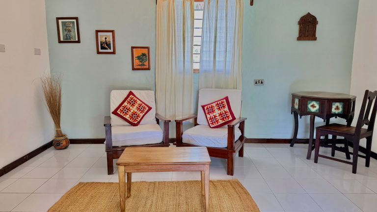 Small sitting room with armchairs in a cottage at Flame Tree Cottages