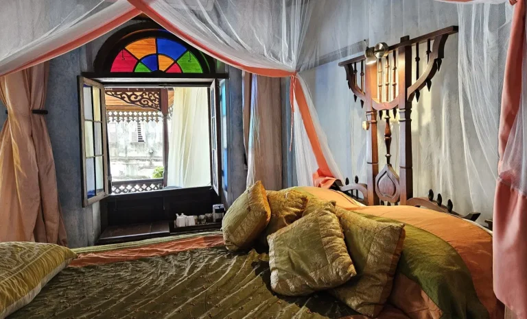 Canopied bed beside an arched stained-glass window at Emerson Spice Hotel