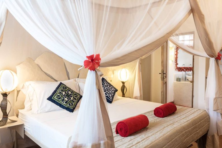 Bright room with canopy bed and red cushions at Villa Kiva