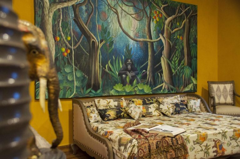 Apartment lounge with a large jungle mural and daybed at Kholle House
